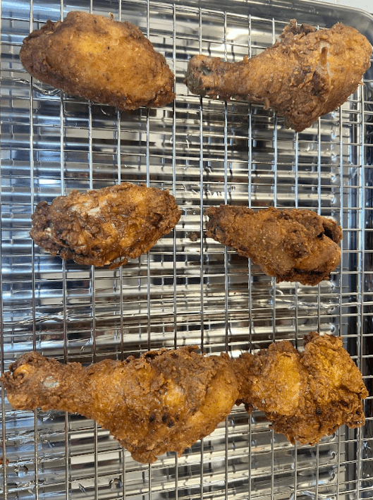 Golden fried chicken pieces on a wire cooling rack over a sheet pan—fresh soul food from Winkie's kitchen